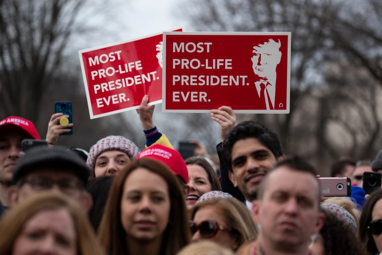Supporters listen and hold up signs as President Donald Trump speaks during the annual "March for Life" rally on the National Mall, Friday, Jan. 24, 2020, in Washington.