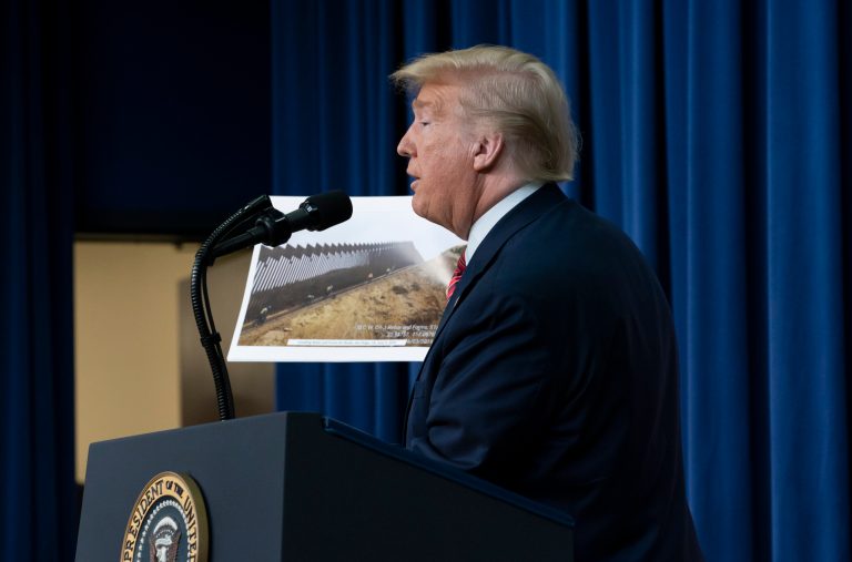 President Donald Trump displays photos of the border wall under construction as he speaks to members of the National Border Patrol Council at the White House Friday.
