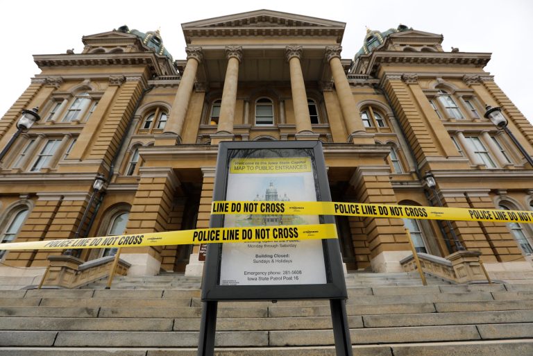 Police tape is wrapped around a sign in front of a closed entrance at the Statehouse in Des Moines, Iowa. Iowa leaders suspended the current legislative session for at least 30 days after learning the state now has community spread of coronavirus.