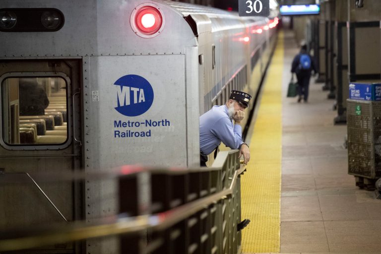 A conductor waits for customers to embark a train at Grand Central Terminal, Tuesday, March 17, 2020, in New York. The Metropolitan Transportation Authority says it is facing a "financial calamity" as ridership on subways and commuter rail lines has nose-dived as people stay home to avoid the new coronavirus.