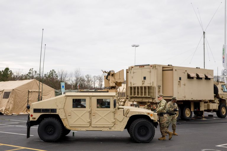 Soldiers with a security unit guard the perimeter as members of the National Guard set up tents to be used for coronavirus testing, Saturday, March 21, 2020, in a parking lot for FedEx Field in Landover, Md., outside of Washington.