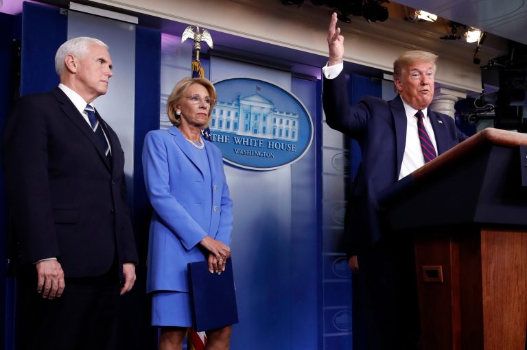 President Donald Trump speaks about the coronavirus in the James Brady Press Briefing Room, Friday, March 27, 2020, in Washington, as Vice President Mike Pence and Education Secretary Betsy DeVos listen. The three are pushing for schools to reopen in the fall.