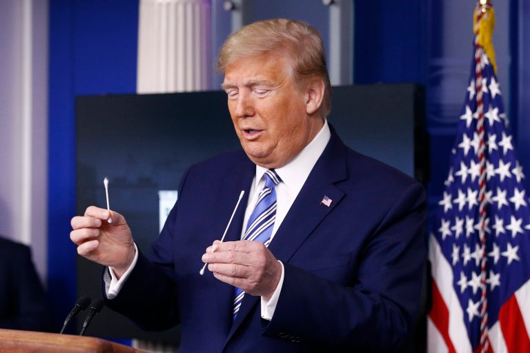President Donald Trump holds swabs, one, right, that could be used in coronavirus testing.