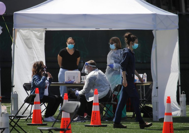 A woman gestures, left, while undergoing a COVID-19 test at Garfield Square Monday, April 27, 2020, in the Mission District of San Francisco.