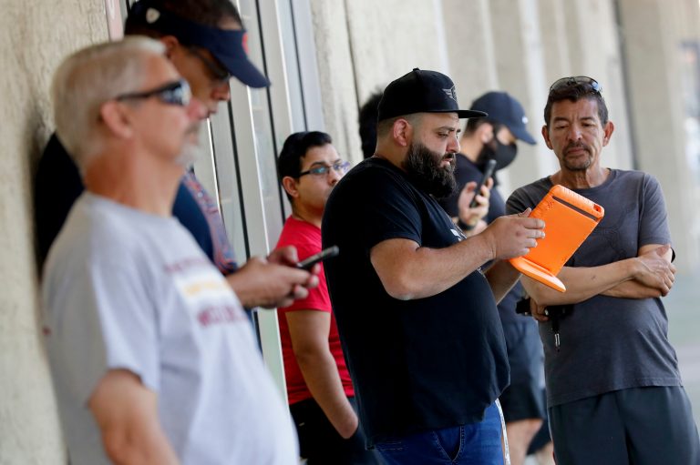 Owner Ronnie Yagudaev takes names for the waiting list outside Uptown Barbershop Friday, May 8, 2020, in Phoenix. A line began hours prior to opening as hair salons and barbershops across Arizona began reopening Friday after being closed for more than a month by order of the governor due to the COVID-19 Coronavirus outbreak.