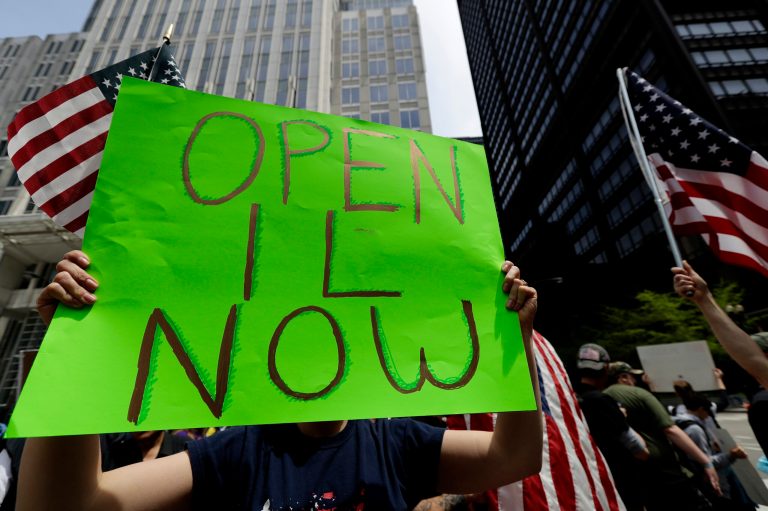 A protester holds a sign during a reopen Illinois rally outside Thompson Center in downtown Chicago, Saturday, May 16, 2020, during the coronavirus pandemic. Many small business believe they can get up and running soon after stay-at-home rules are lifted.