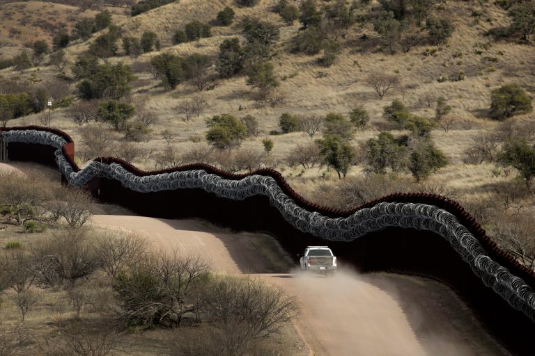 This March 2, 2019, file photo, shows a Customs and Border Control agent patrolling on the US side of a razor-wire-covered border wall along the Mexico east of Nogales, Ariz. Battleground voters in a new survey support the administration's immigration pause to help unemployed Americans get re-hired.