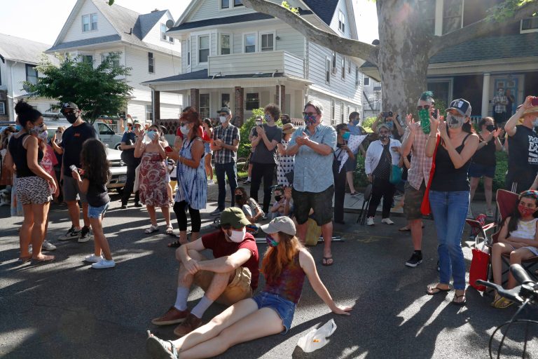 People applaud while listening to an outdoor concert performed by 10 musicians in front of Roy Nathanson's home, part of Make Music-New York in Brooklyn's Ditmas Park neighborhood during the coronavirus outbreak, Sunday, June 21, 2020, in New York. As states weaken virus control, some have seen a spike in new virus cases.
