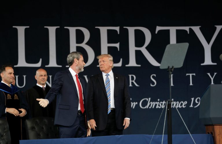 President Donald Trump stands on stage with Liberty University President Jerry Falwell, third from left, after giving the commencement address in May 2017. A suit by the school said the New York Times targets it because of its politics and ties to Trump.