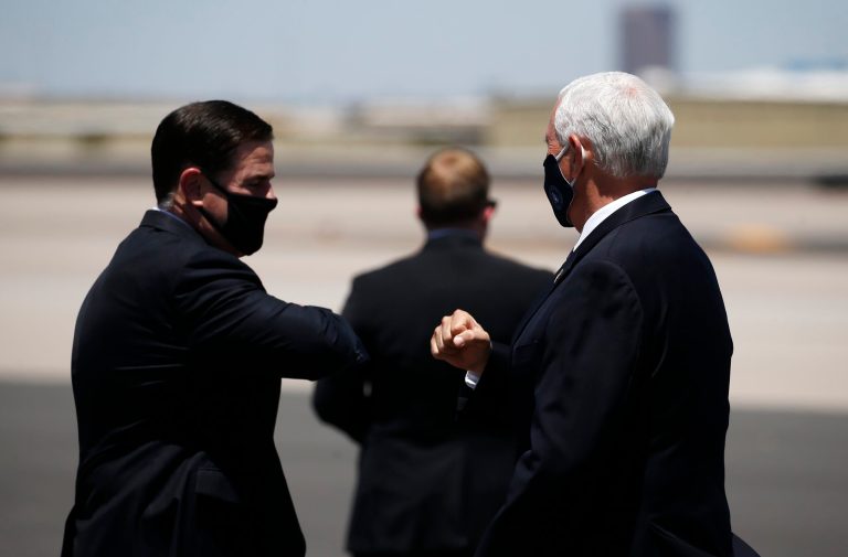 Vice President Mike Pence, right, is greeted with an elbow bump by Arizona Gov. Doug Ducey, left, as he arrives to discuss the surge in coronavirus cases Wednesday.
