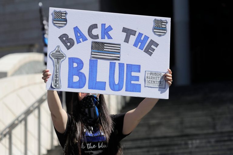A person holds a sign that reads "Back the Blue," during a rally in support of police and other law enforcement officers, Wednesday, July 15, 2020, in front of City Hall in Seattle. The nation is debating policing.