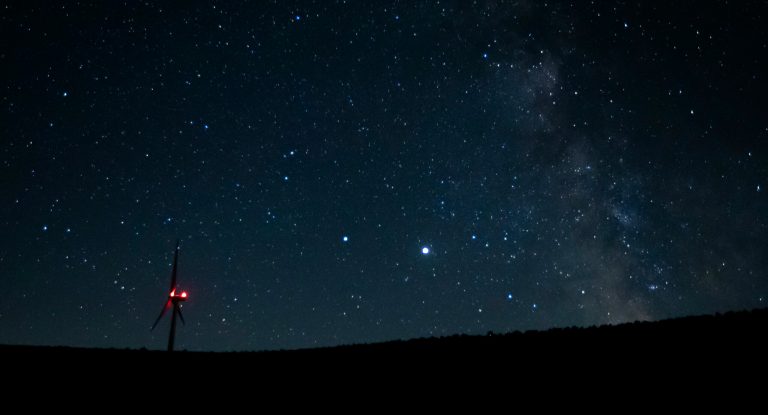 The planets Saturn, center-left, and Jupiter, center-right, are shown between a wind turbine and Milky Way just after midnight, Monday, July 27, 2020, near Vantage, Washington. (AP Photo/Ted S. Warren)