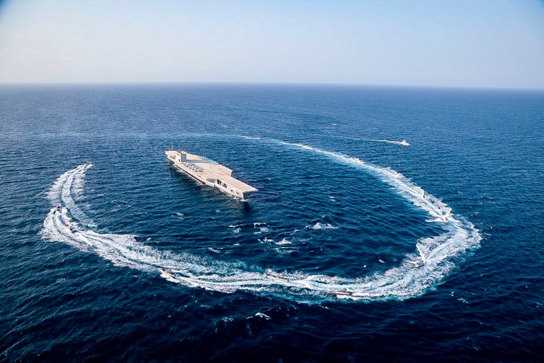 In this photo released Tuesday, July 28, 2020, by Sepahnews, Revolutionary Guard's speed boats circle around a replica aircraft carrier during a military exercise. Iranâs paramilitary Revolutionary Guard fired a missile from a helicopter targeting the mock-up aircraft carrier in the strategic Strait of Hormuz according to footage aired on state television on Tuesday.