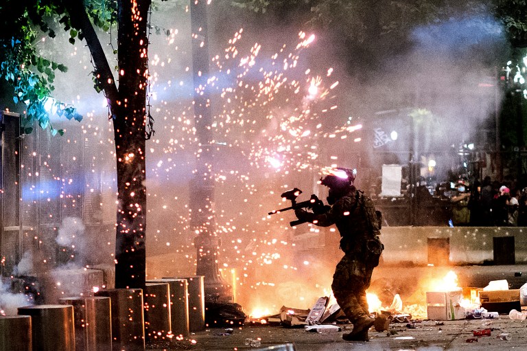 A federal officer faces Black Lives Matter protesters at the Mark O. Hatfield United States Courthouse on Friday, July 24, 2020, in Portland, Ore. Americans expect to see post-election violence.