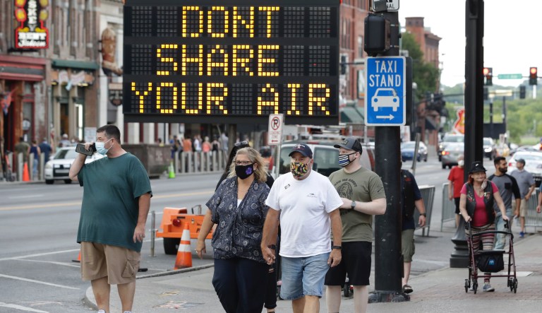 A sign encouraging the wearing of masks and keeping social distancing stands at a street corner Wednesday, Aug. 5, 2020, in downtown Nashville, Tenn. The wearing of face coverings is required in most public indoor and outdoor situations in Nashville due to an increase of COVID-19 cases.