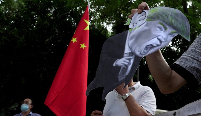 In this Aug. 8, 2020, file photo, pro-China supporters display a picture of U.S. President Donald Trump during a protest against the U.S. sanctions outside the U.S. Consulate in Hong Kong. 
