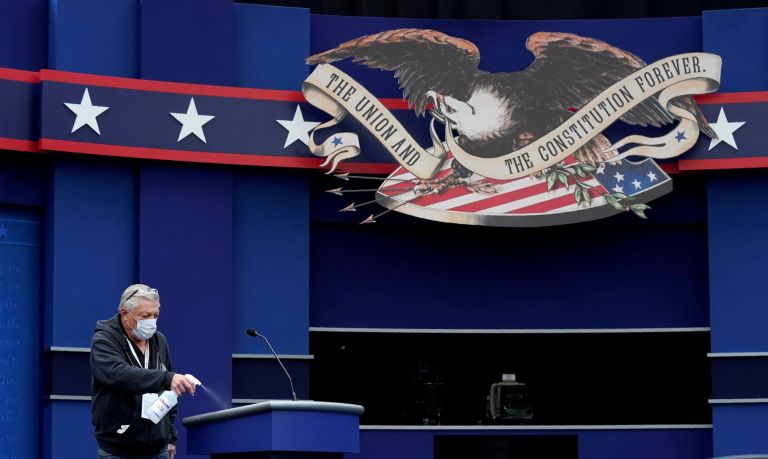 A worker sprays sanitizer on a lectern as preparations take place for the first Presidential debate in the Sheila and Eric Samson Pavilion, Monday, Sept. 28, 2020, in Cleveland. (AP Photo/Patrick Semansky)