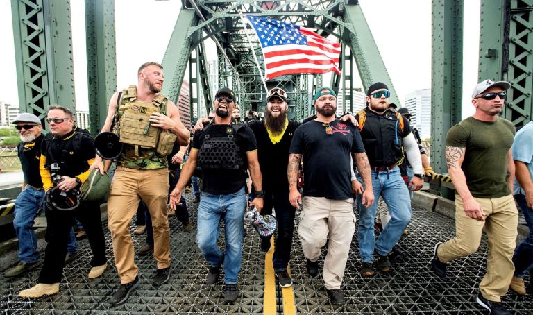 Members of the Proud Boys and other right-wing demonstrators march across the Hawthorne Bridge during an "End Domestic Terrorism" rally in Portland, Ore, last year. The group includes organizer Joe Biggs, center in green hat, and Proud Boys Chairman Enrique Tarrio, holding megaphone.