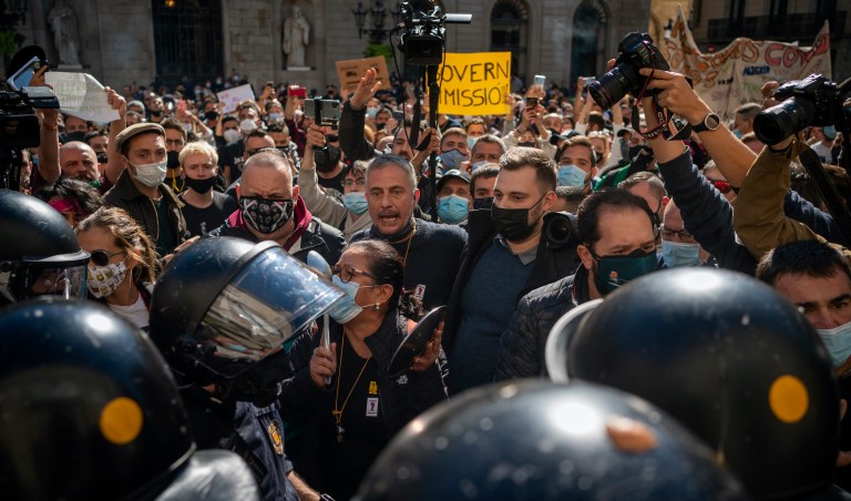 Workers of catering sectors clash with police officers during a protest organised by restaurants and bar owners in Barcelona, Spain, Friday Oct. 16, 2020. Bars and restaurants close from Friday and for two weeks in Spain's northeastern Catalonia region, while other cities impose or prepare for soft lockdowns amid one of Europe's sharpest resurgences of the new coronavirus. (AP Photo/Emilio Morenatti)