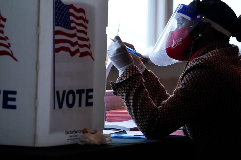 A poll worker talks to a voter before they vote on a paper ballot on Election Day in Atlanta on Tuesday, Nov. 3, 2020.