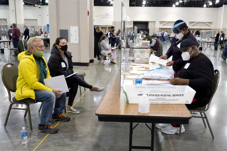 Election workers, right, verify ballots as recount observers, left, watch during a Milwaukee hand recount of presidential votes at the Wisconsin Center, Friday, Nov. 20, 2020, in Milwaukee. The recount of the presidential election in Wisconsin's two most heavily Democratic counties began Friday with President Donald Trump's campaign seeking to discard tens of thousands of absentee ballots that it alleged should not have been counted.