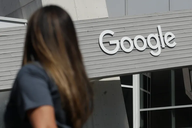 A woman walks below a Google sign on the campus in Mountain View, Calif. In the years since Barack Obama and Joe Biden left the White House, the tech industry's political fortunes have flipped. Facebook, Google, Amazon and Apple have come under scrutiny from Congress, federal regulators, state attorneys general and European authorities. 