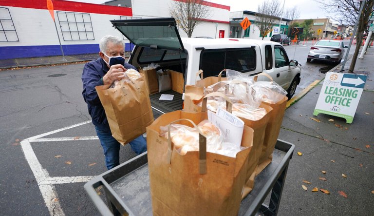 Fred Delaurenti, a volunteer driver with Meals on Wheels, prepares to make a delivery at an apartment building, Wednesday, Dec. 9, 2020 in Renton, Wash., south of Seattle. Nationally, Meals on Wheels America said its 5,000 community programs are, on average, serving more meals this year compared to in 2019, and nearly all of them are facing financial strain because the COVID-19 pandemic has also forced them to buy additional safety equipment and pay drivers to replace volunteers. 