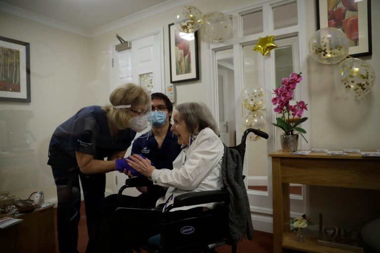 Care home resident Joan Potts, aged 102, is seen through a viewing screen installed for residents to safely receive visits from family members, as she speaks to Dr. Jane Allen after receiving her first dose of the Oxford/AstraZeneca COVID-19 vaccine at the Wimbledon Beaumont Care Home, run by Barchester, in southwest London, Wednesday, Jan. 13, 2021.