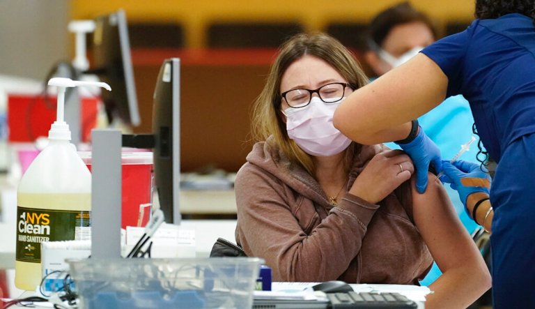 A health care worker, gives a coronavirus vaccine to a patient at a COVID-19 vaccination site at the Aqueduct Race Track, Thursday, Jan. 21, 2021, in the Queens borough of New York. New York City Mayor Bill de Blasio said Tuesday, Jan. 21,  that the city will run out of first doses of COVID-19 vaccine sometime Thursday without fresh supplies.