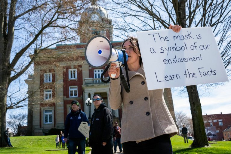 Rachel Powell, of Sandy Lake, Pa., uses a bullhorn to talk to passing cars while protesting stay-at-home orders and the shutdown of non-essential businesses due to the coronavirus pandemic outside the Mercer County Courthouse, on April 20, 2020, in Mercer, Pennsylvania.