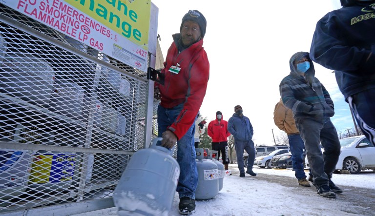 In this Feb. 16, 2021, file photo, Robert Webster pulls a full canister of propane for sale as customers line up to enter a grocery store in Dallas.