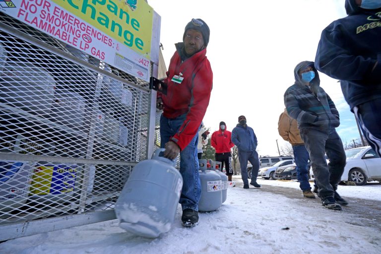 Robert Webster pulls a full canister of propane for sale as customers line up to enter a grocery store in Dallas, Texas on Feb. 16. 