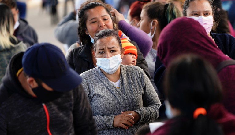 A woman waits for food handouts from a local church at a makeshift camp for migrants seeking asylum in the United States at the border crossing Friday, March 12, 2021, in Tijuana, Mexico.