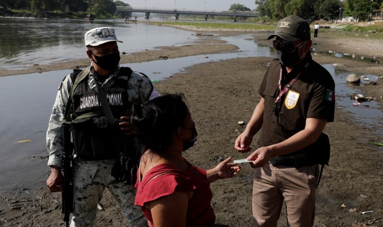 Mexican immigration agents review the identification of a Guatemalan woman at an access point to the Suchiate River, the natural border between Guatemala and Mexico, near Ciudad Hidalgo, Mexico, Sunday, March 21, 2021. Mexico sent hundreds of immigration agents, police, and National Guard members to its southern border to launch an operation to crack down on migrant smuggling.