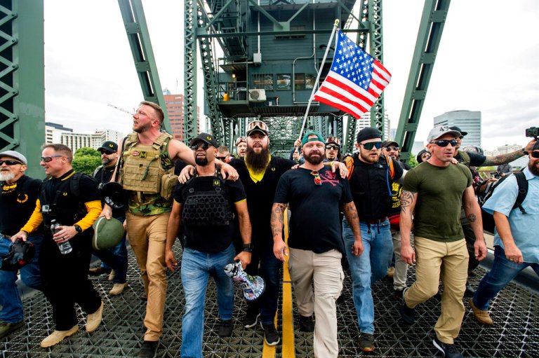 In this Aug. 17, 2019, file photo, organizer Joe Biggs (wearing a green hat) and Proud Boys Chairman Enrique Tarrio (holding a megaphone) march with members of the Proud Boys and other right-wing demonstrators across the Hawthorne Bridge during a rally in Portland, Oregon.