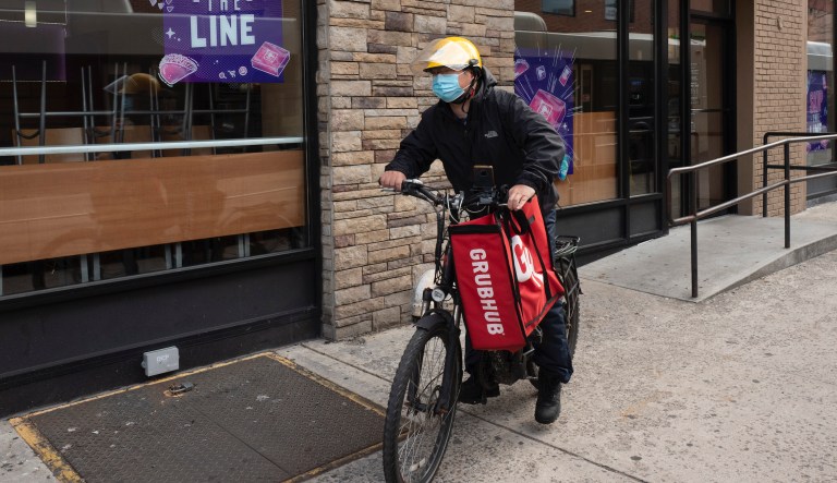 A delivery man bikes with a food bag from Grubhub, Wednesday, April 21, 2021 in New York.