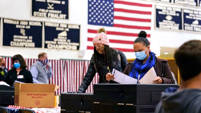âFILEâ In this Tuesday Nov. 3, 2020 file photograph, two women, wearing protective masks due to the COVID-19 virus outbreak, cast their ballots at a polling station at Windham, N.H. High School.