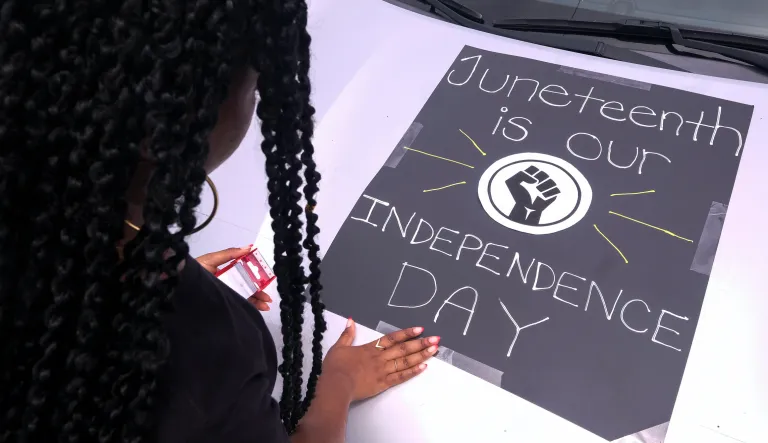 A woman decorates her car with a sign during a car parade to mark Juneteenth on Saturday, June 19, 2021, in Inglewood, Calif.