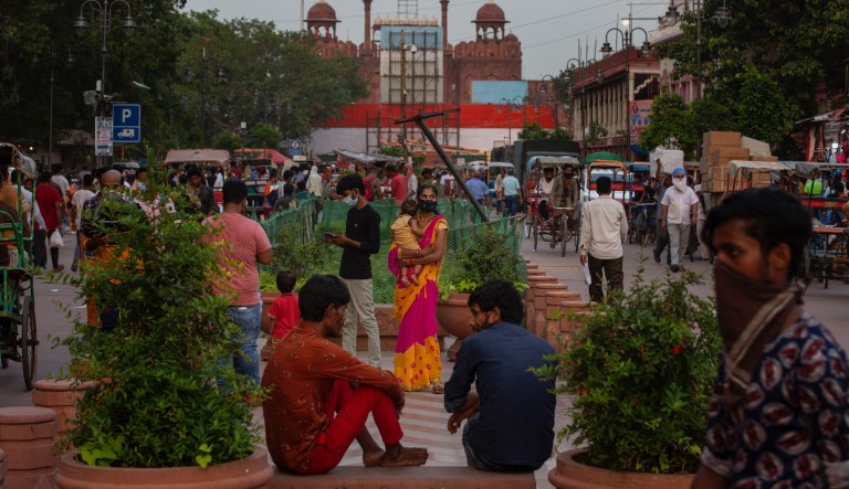 A woman holds a child at a market place in the backdrop of Red Fort, which is blocked by shipping containers, where India's prime minister Narendra Modi will deliver Independence Day speech on August 15, in New Delhi, India, Tuesday, Aug. 10, 2021.