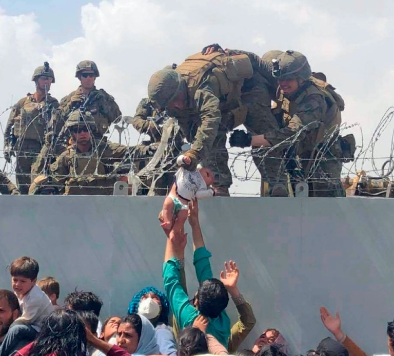 In this image from video provided by Omar Haidari and taken on Thursday, Aug. 19, 2021 which shows a baby being lifted across a wall at Kabul Airport in Afghanistan by US soldiers. The image grabbed from footage, taken on Thursday, showed the infant being pushed up to the soldiers by people in the crowd gathered outside the airport, amid the chaos of those fleeing the Taliban takeover of the country. 