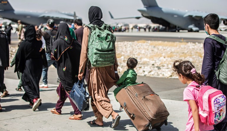 In this Aug. 24, 2021, file photo,  provided by the U.S. Marine Corps, families walk towards their flight during ongoing evacuations at Hamid Karzai International Airport, Kabul, Afghanistan.
