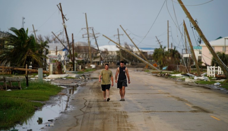 People walk through a neighborhood damaged by Hurricane Ida, Monday, Sept. 6, 2021, in Grand Isle, La.