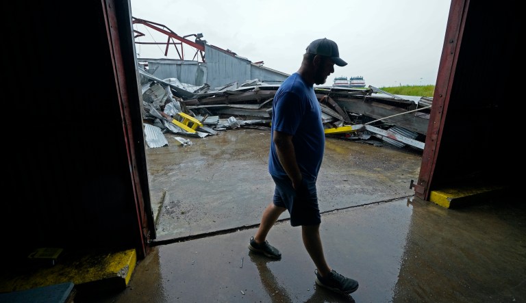 Jarod Voisin walks through damage of his family's heavily damaged oyster processing plant, as rain from Tropical Storm Nicholas, currently in the Gulf of Mexico, comes down, in the aftermath of Hurricane Ida in Houma, La., Tuesday, Sept. 14, 2021.