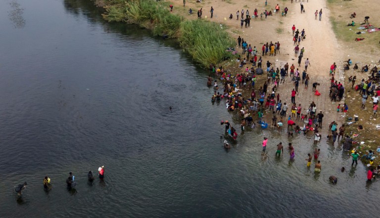Migrants, many from Haiti, are seen wading between the United States and Mexico on the Rio Grande on Sept. 21, 2021, in Del Rio, Texas.