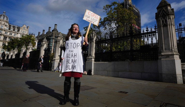 A lone climate demonstrator holds a banner outside parliament in London, Monday, Oct. 25, 2021, ahead of the UN climate conference COP26 that will be held in Glasgow, Scotland, next week.