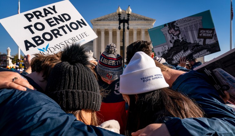 A group of anti-abortion protesters pray together in front of the U.S. Supreme Court, Wednesday, Dec. 1, 2021, in Washington, as the court hears arguments in a case from Mississippi, where a 2018 law would ban abortions after 15 weeks of pregnancy, well before viability.