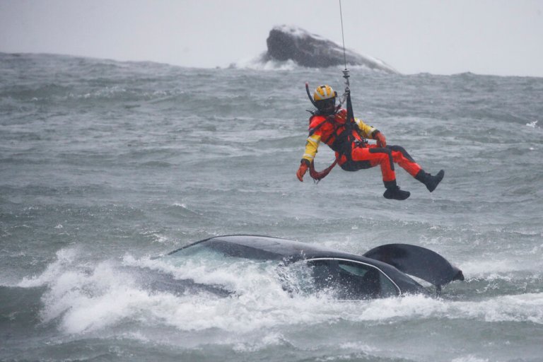 A Coast Guard diver is lowered from a hovering helicopter to pull a body from a submerged vehicle stuck in rushing rapids just yards from the brink of American Falls, one of three waterfalls that make up Niagara Falls, Wednesday in Niagara Falls, New York.