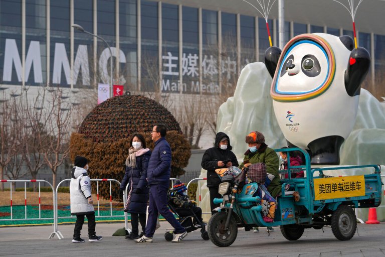 People wearing face masks to protect from the coronavirus walk by a Beijing Winter Olympics mascot on display near the barricaded Main Press Center (MPC) in Beijing, Wednesday, Jan. 19, 2022. China has locked down parts of Beijing's Haidian district following the detection of three cases, just weeks before the capital is to host the Winter Olympic Games.