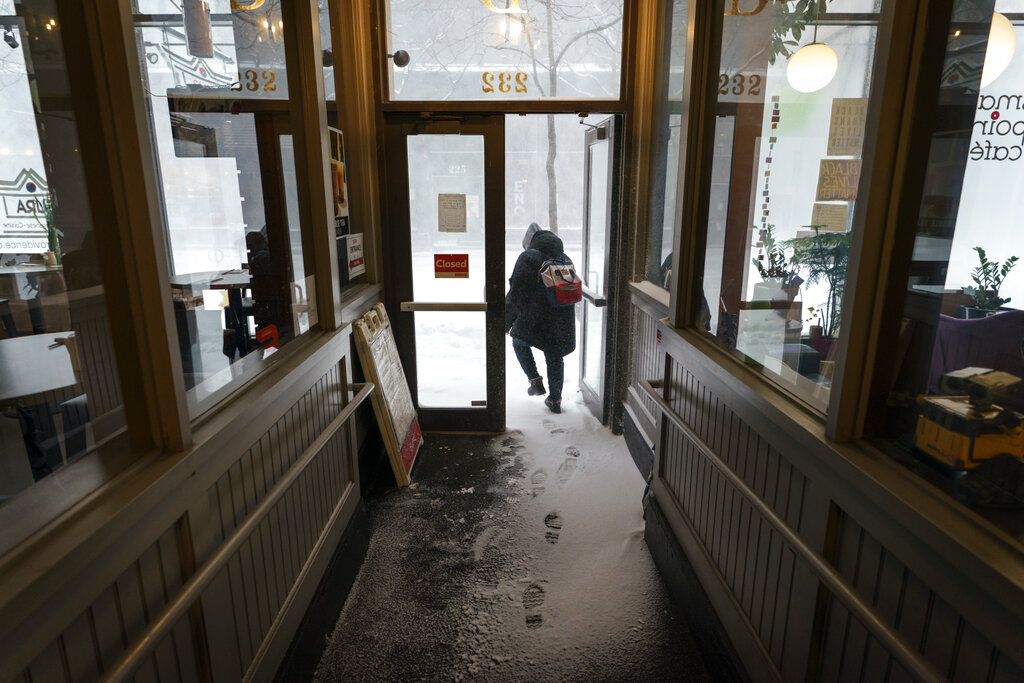 A patron walks through a snow drift in a doorway while leaving a coffee shop in Providence, Rhode Island, on Saturday.