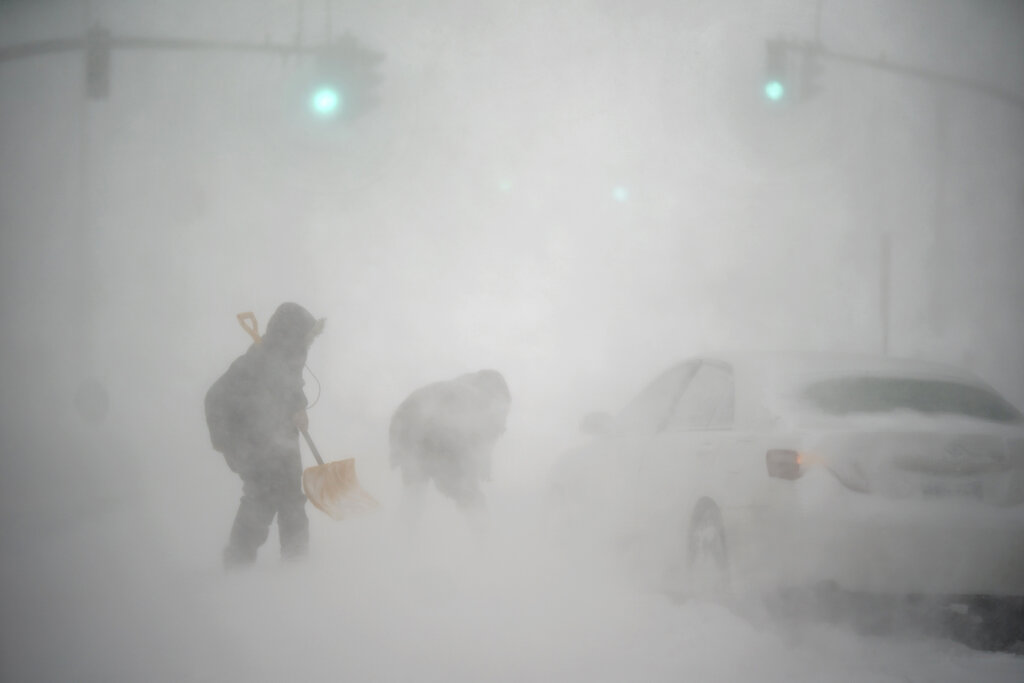 A stranded motorist, at right, gets help shoveling out their car from a passerby with a shovel in Providence, Rhode Island, Saturday.